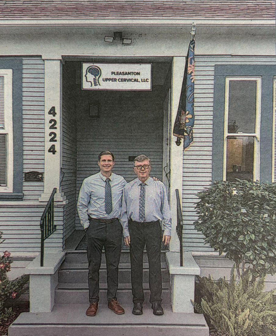 Two doctors standing on the front steps of the office under the Pleasanton Upper Cervical sign